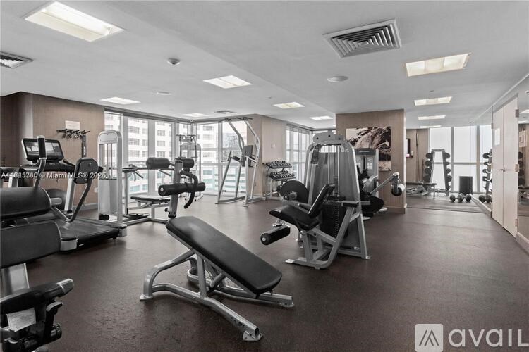 A gym with a variety of equipment including treadmills, weights, and benches.