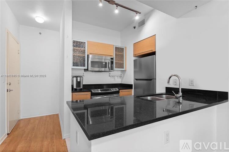 A kitchen with a black countertop and stainless steel appliances.