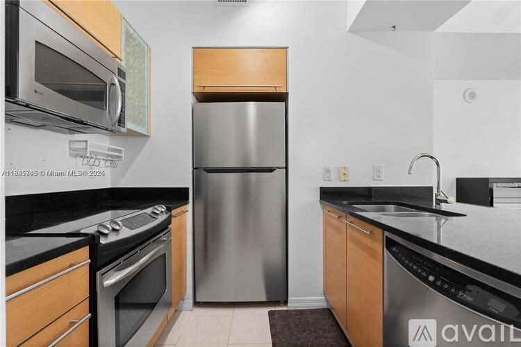 A kitchen with a stainless steel refrigerator, microwave, oven, and sink.