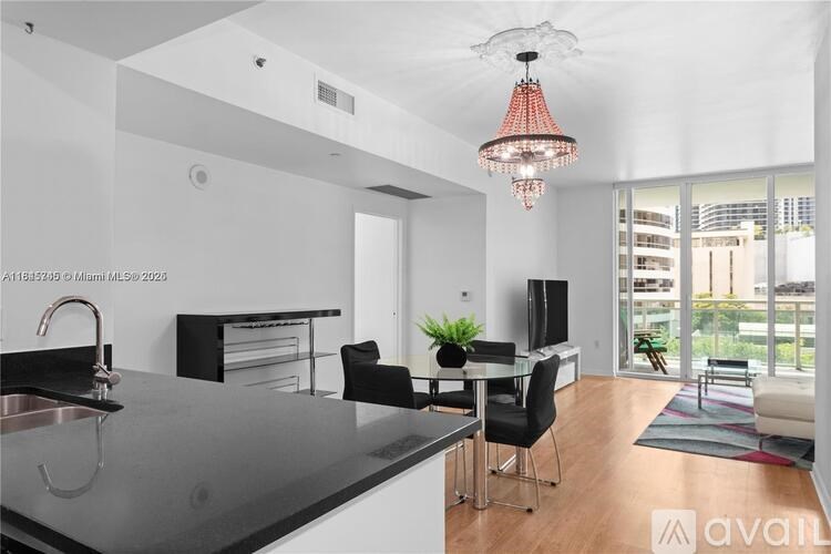 A modern kitchen with a black countertop and a glass chandelier hanging from the ceiling.