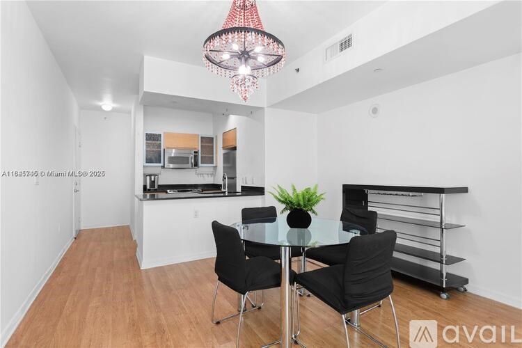 A modern kitchen with a glass table and black chairs.