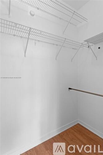 A room with white walls and wooden flooring with a metal rack on the ceiling.