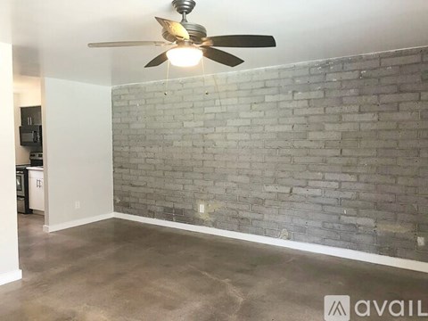 A room with a ceiling fan and a brick wall.