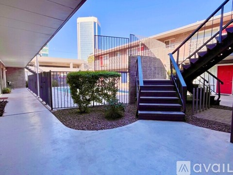 A staircase with a metal railing leads up to a red door.