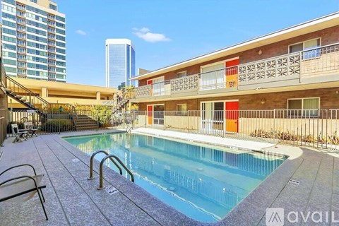 A pool area with a clear blue pool and a building in the background.