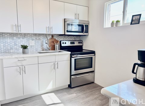 A kitchen with white cabinets and a black stove top oven.
