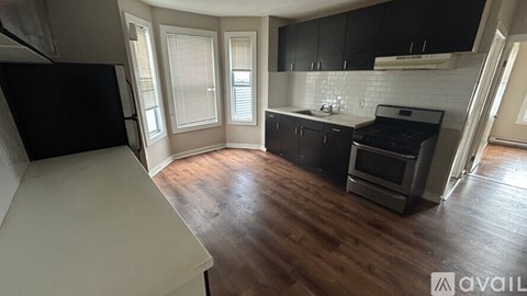 A kitchen with black cabinets and a white fridge is available for rent.