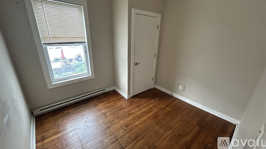 A room with wooden floors and a window with blinds.