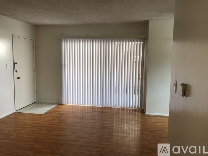 A room with a wooden floor and a window with blinds.