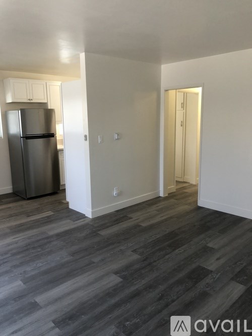 A kitchen with a refrigerator and a hallway with a door.