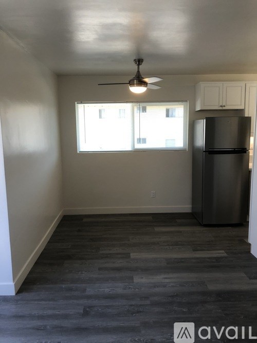 A room with a refrigerator and a ceiling fan.