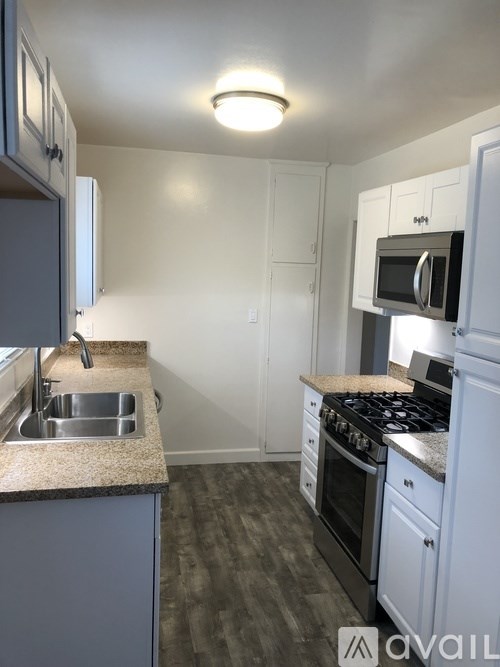 A kitchen with a sink, stove, and microwave.