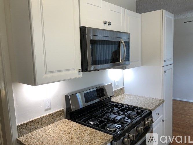 A kitchen with a black microwave oven mounted above a black gas stove.