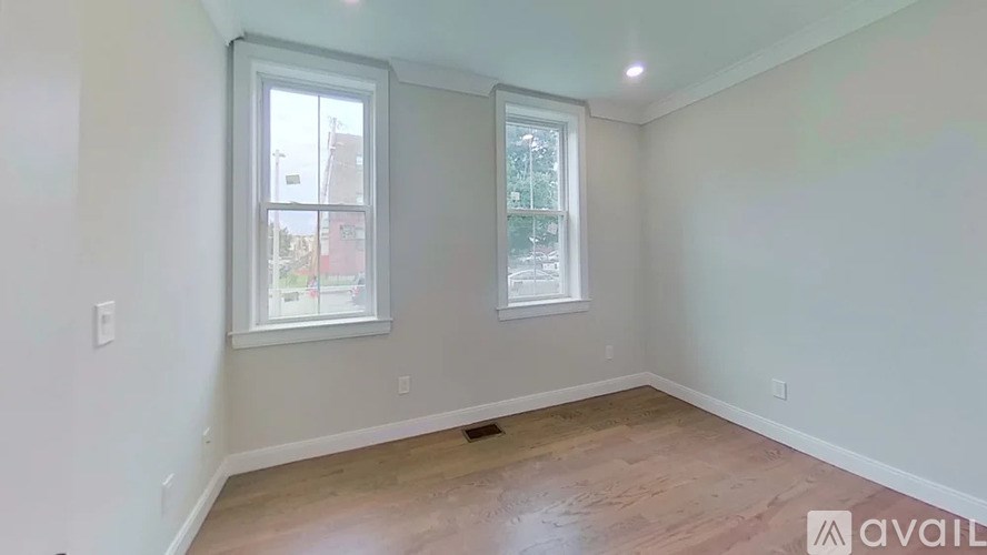 A room with two windows and wooden flooring is available for rent.