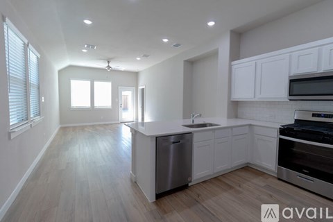 A modern kitchen with white cabinets and a wooden floor.