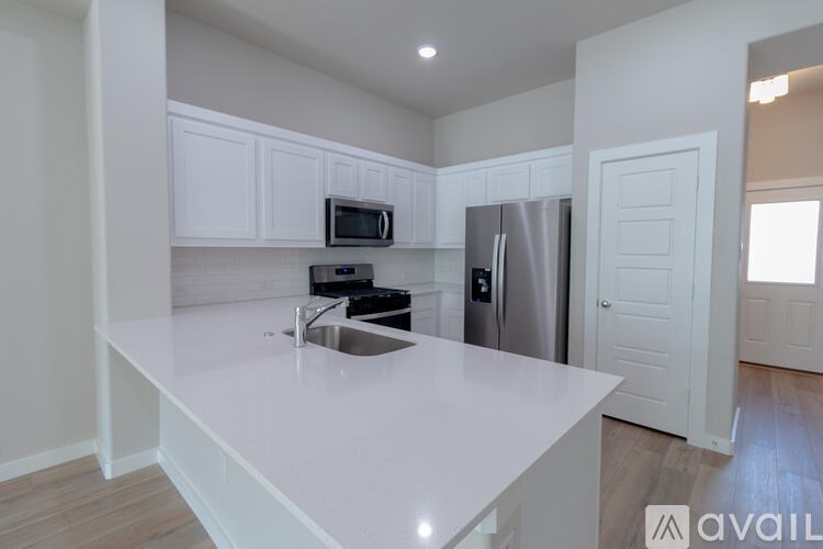 A kitchen with white countertops and a stainless steel refrigerator.