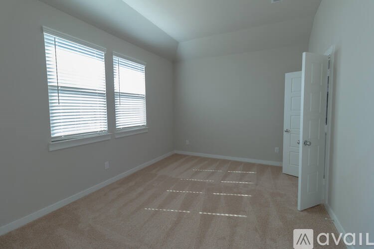 A room with a carpet on the floor and a door on the right side.