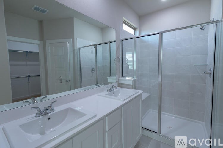 A bathroom with a white sink and a glass shower stall.