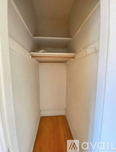 A white hallway with a wooden floor and a white ceiling.