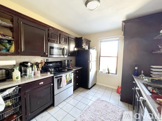 A kitchen with black appliances and brown cabinets.