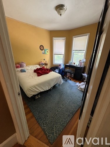 A bedroom with a bed, desk, and window.