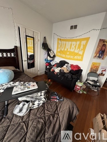 A room with a bed, a chair, and a poster on the wall.