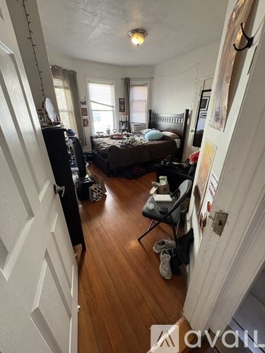 A bedroom with a bed, chair, and a window.