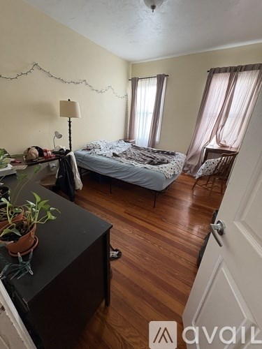 A bedroom with a bed, chair, and a desk.