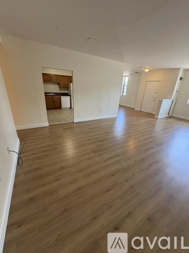 A spacious room with wooden flooring and white walls.