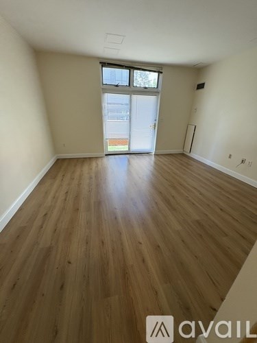 A room with wooden flooring and a window with a view of a building outside.