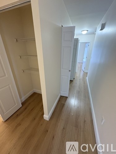 A hallway with white walls and wood flooring.