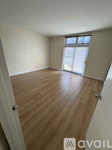 A room with wooden flooring and a sliding glass door.