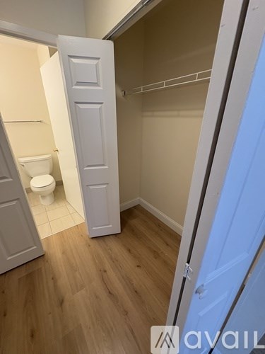 A white door is open to a bathroom with a toilet and a walk-in shower.