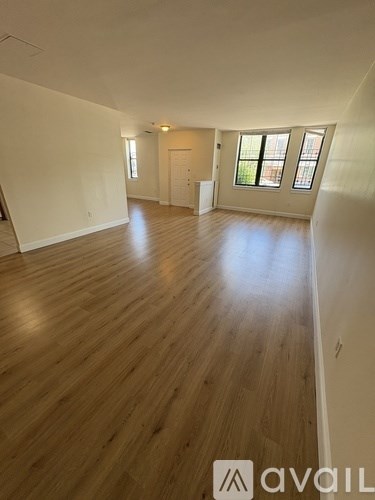 A spacious room with wooden flooring and a window.