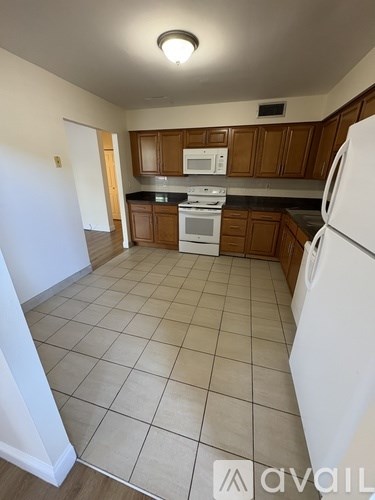 A kitchen with white appliances and brown cabinets.