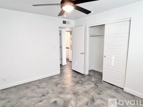 A room with a ceiling fan and a door leading to another room.