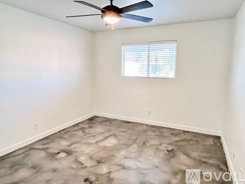 A room with a ceiling fan and a window with blinds.