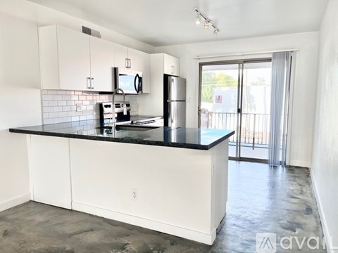 A kitchen with white cabinets and black countertops.