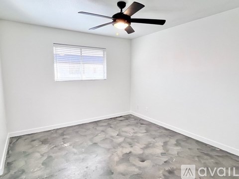 A room with a ceiling fan and a window with blinds.
