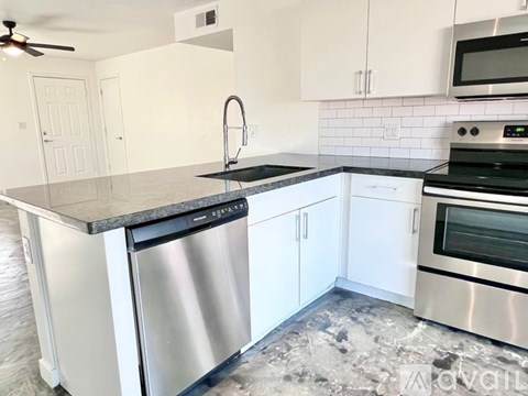 A kitchen with white cabinets and a black countertop.