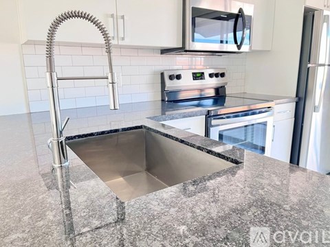 A kitchen with a stainless steel sink and a stove top oven.