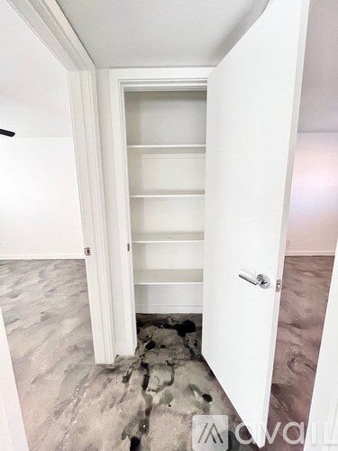 A white door with a handle is open to a hallway with a marble floor.