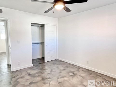 A room with a ceiling fan and a door leading to a bathroom.