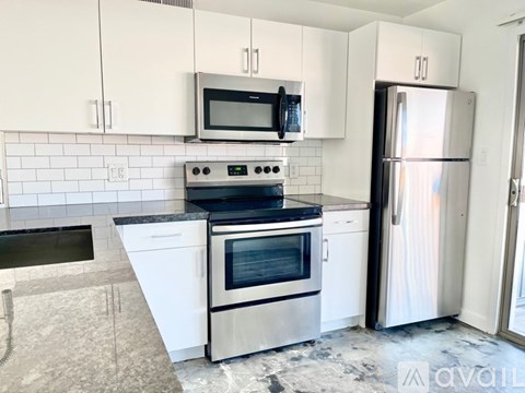 A kitchen with white cabinets and a stainless steel refrigerator.
