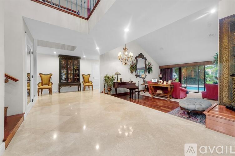A spacious living room with a grand piano and a staircase.