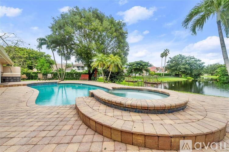 A large outdoor swimming pool surrounded by a brick patio and palm trees.