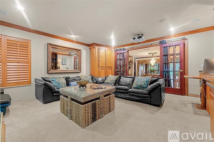 A living room with a black couch, a glass coffee table, and a large mirror on the wall.