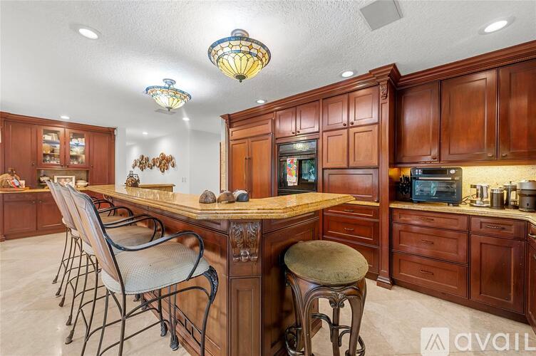 A kitchen with wooden cabinets and a central island with a countertop and bar stools.
