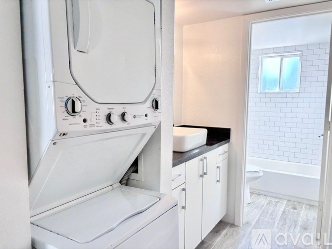 A white dryer is in a small laundry room with a window.