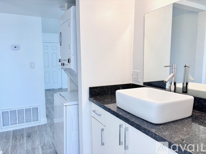 A white bathroom with a sink, mirror, and a white door.